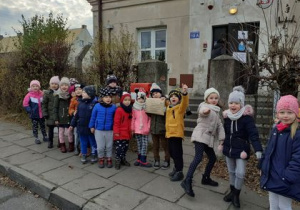 dzieci stoją przed budynkiem poczty, wysyłają paczkę do Olsztyna