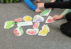 grupa chłopców segreguje obrazki z warzywami i owocami