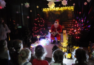 w zimowej aranżacji siedzi Mikołaj na specjalnie przygotowanym fotelu, obok stoją dzieci