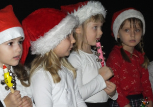 kilkoro dzieci stoi i śpiewa Mikołajowi piosenkę