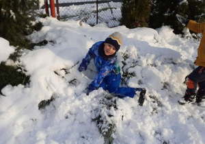 chłopiec leży w śniegu, uśmiecha się