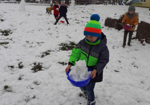 chłopiec niesie miskę pełną śniegu