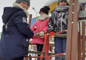 trzy dziewczynki wspięły się na drabiki na placu zabaw