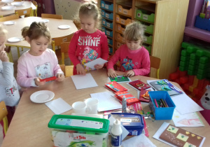 dzieci przy stole segregują materiały do kartek