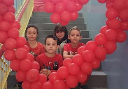 kilkoro dzieci pozuje do zdjęcia w sercu z balonów