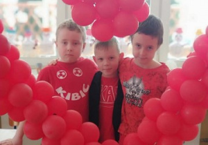 kilku chłopców pozuje do zdjęcia w sercu z balonów