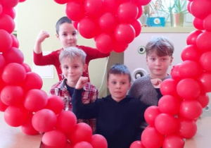 kilku chłopców pozuje do zdjęcia w sercu z balonów