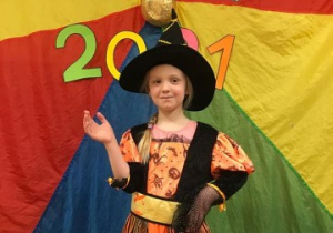 dziewczynka przebrana za czarownicę pozuje do zdjęcia na tle kolorowej chusty animacyjnej