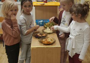 4 dziewczynki próbują różnych owoców przygotowanych na talerzu