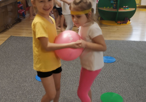 dwie dziewczynki ćwiczą z piłką