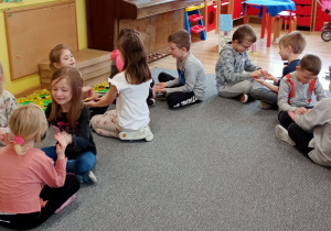 dzieci siedzą parami na dywanie klaszczą w ręce