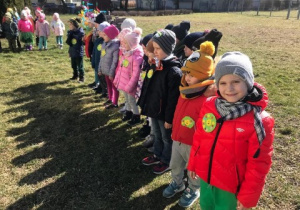 grupa dzieci stoi w przedszkolnym ogrodzie, uczestniczy w powitaniu wiosny