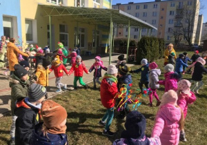 grupa dzieci tańczy w przedszkolnym ogrodzie, uczestniczy w powitaniu wiosny