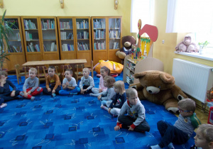 grupa dzieci siedzi na dywanie w czytelni