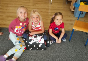 trzy dziewczynki siedzi na dywanie , mają na sobie ubrania w kropki