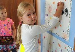 dziewczynka maluję kropkę na papierze przymocowanym do ściany w szatni