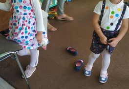 dwie dziewczynki, w ubraniach w kropki stoją na dywanie