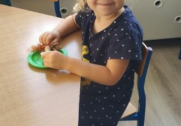 dziewczynka w ubraniu w kropki siedzi przy stoliku w klasie