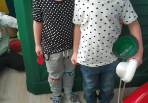 dwóch chłopców stoi przy domku do zabawy