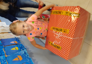 dziewczynka niesie wielkie pudło, ozdobione papierem w kropki