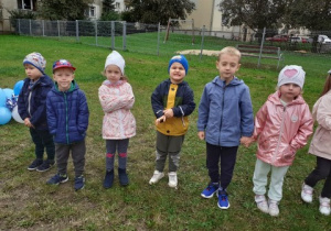 grupa 6 dzieci stoi na podwórku przedszkolnym