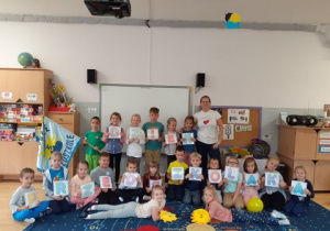 grupa najstarszych dzieci pozyje do zdjęcia w klasie , w rękach trzymają litery układające się w napis "dzień przedszkolaka"