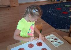 dziewczynka maluje farbami brązowe koła - środki słoneczników