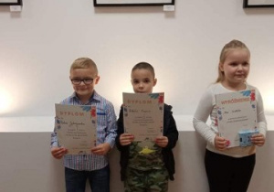sala MOK w Ozorkowie, troje dzieci - laureatów pozuje do zdjęcia z dyplomami