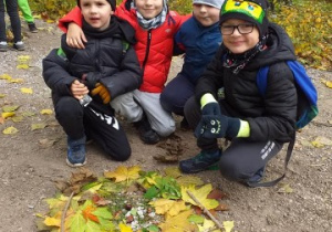 czterech chłopców kuca, przed nimi wykonana z liści mandala