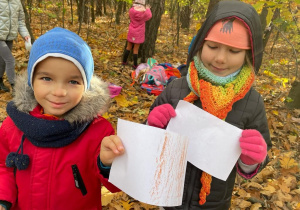 dziewczynka i chłopiec pokazują wykonany na korze drzew frottage
