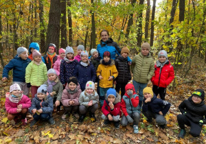 grupa dzieci i nauczycielka pozuje do zdjęcia w lesie