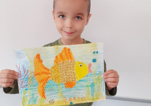 Chłopiec prezentuję swoją pracę "Złota rybka"