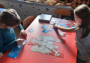 dwie dziewczynki siedzą przy stoliku, układają puzzle - godło