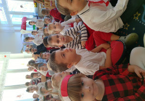 grupa dzieci, ubrane w biało-czerwone ubrania, mają opaski, wianki, rozety w barwach narodowych
