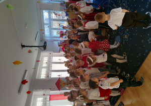 grupa dzieci ubranych w biało-czerwone ubrania ogląda program muzyczny o tematyce patriotycznej