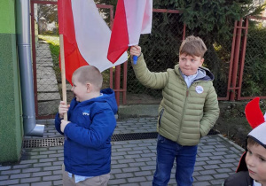 dwaj chłopcy na dworze, w rękach trzymają flagi