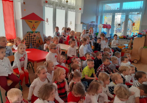 grupa dzieci w biało-czerwonych ubraniach ogląda patriotyczny program słowno - muzyczny