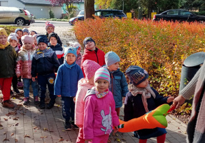 grupa dzieci , w parach, trzyma "węza spacerowego", idą chodnikiem