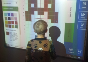 chłopiec przy tablicy interaktywnej, koduje schemat misia