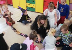 dzieci i nauczycielka przebrana za czarownicę układają buty jeden za drugim