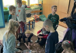 dzieci zgormadzone wokół srebrnej misy z wodą, zbierają konfetti z dywanu