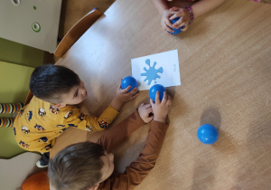 chłopcy przykładają niebieską piłkę do obrazka z niebieskim kolorem