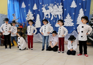 grupa chłopców przebranych za bałwanki, na tle świątecznej dekoracji