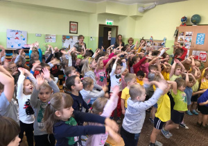 dzieci stoją z podniesionymi rękami i bawią się z aktorami