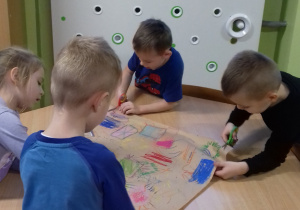 grupa dzieci pracuje pastelami przy stoliku