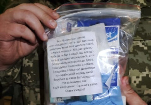 żołnierz UA pokazuje zestaw opatrunkowy i list w j. ukraińskim, jaki napisaliśmy dla żołnierzy