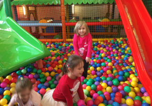 grupa dzieci bawi się w kolorowych piłkach