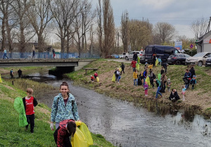 rodzice wraz z dziećmi zbierają śmieci wzdłuż rzeki
