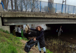 kobieta zbiera śmieci wzdłuż rzeki