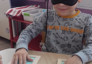 chłopiec z opaską na oczach dotyka domino z fakturami